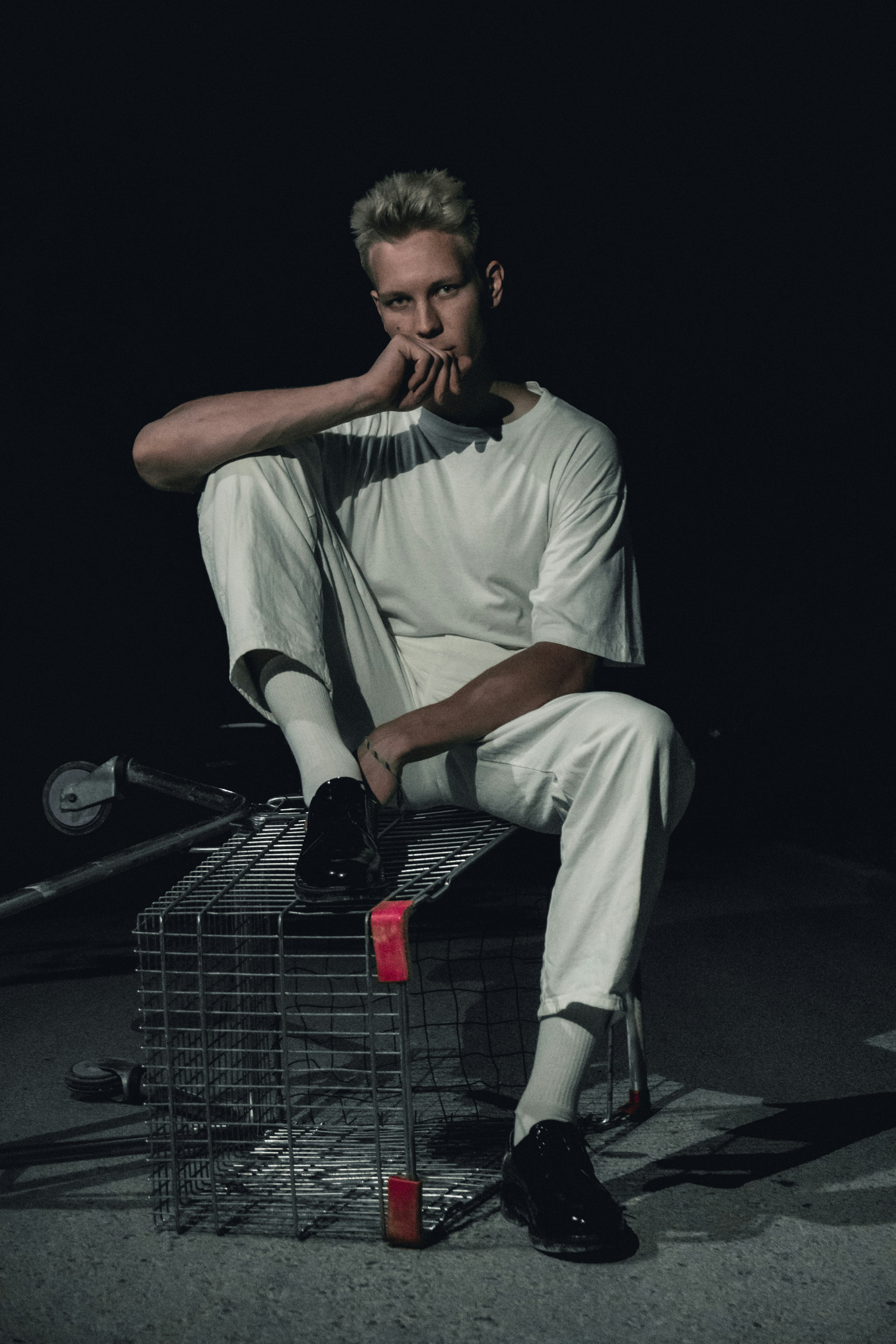 man in white polo shirt and beige pants sitting on shopping cart